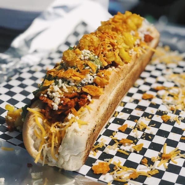 El Burro Loco's Mexican hot dog, topped with chili, cheese, and crushed chips on checkered paper.