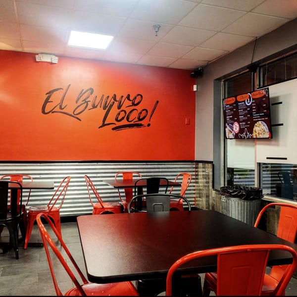 El Burro Loco's dining area with orange walls, black tables, red chairs, and a digital menu.