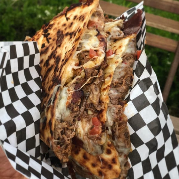 El Burro Loco's quesadilla, filled with shredded meat, melted cheese, and diced tomatoes, wrapped in checkered paper.