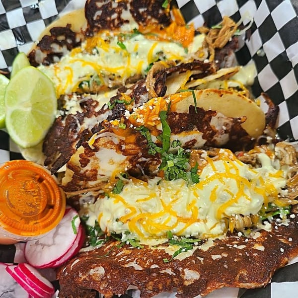 Three El Burro Loco tacos with melted cheese, cilantro, lime, and a side of sauce and radishes.